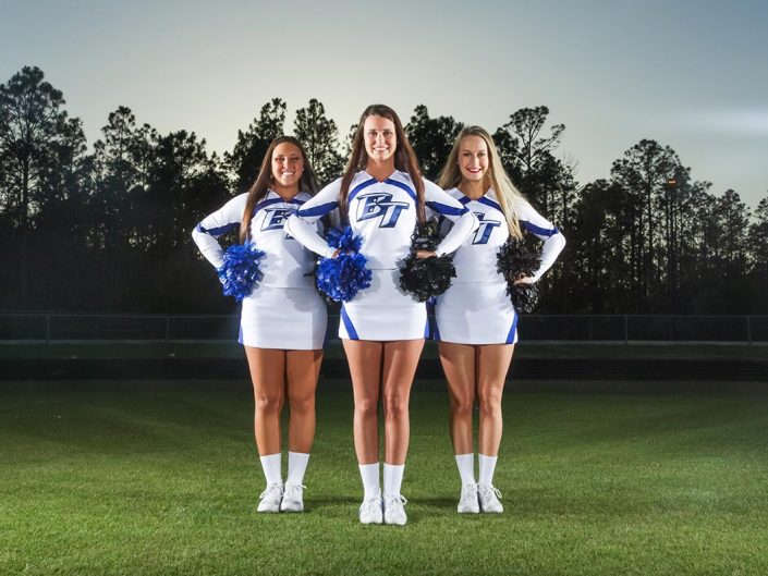 Athletic Gallery - Three women in white and blue cheerleading uniforms