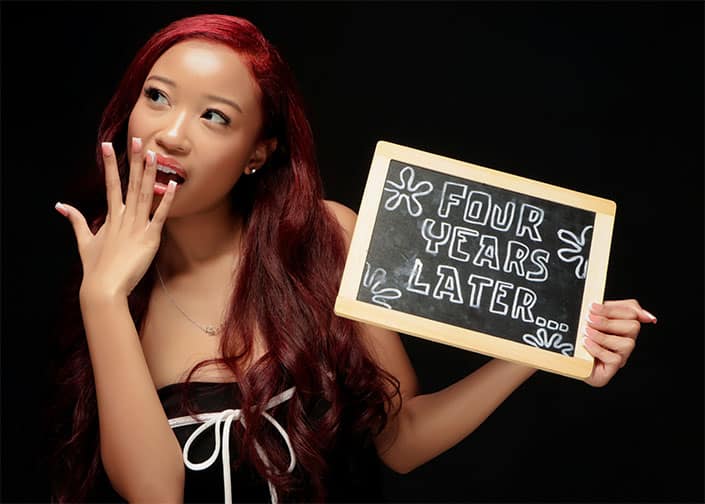 Person with red hair holding a chalkboard sign that reads "FOUR YEARS LATER."