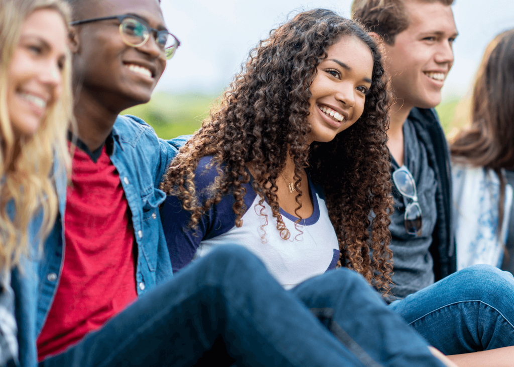 Group of young people sitting together casually outdoors.