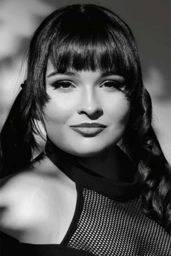 Monochrome portrait of a person with braided hair, wearing a mesh-top outfit.